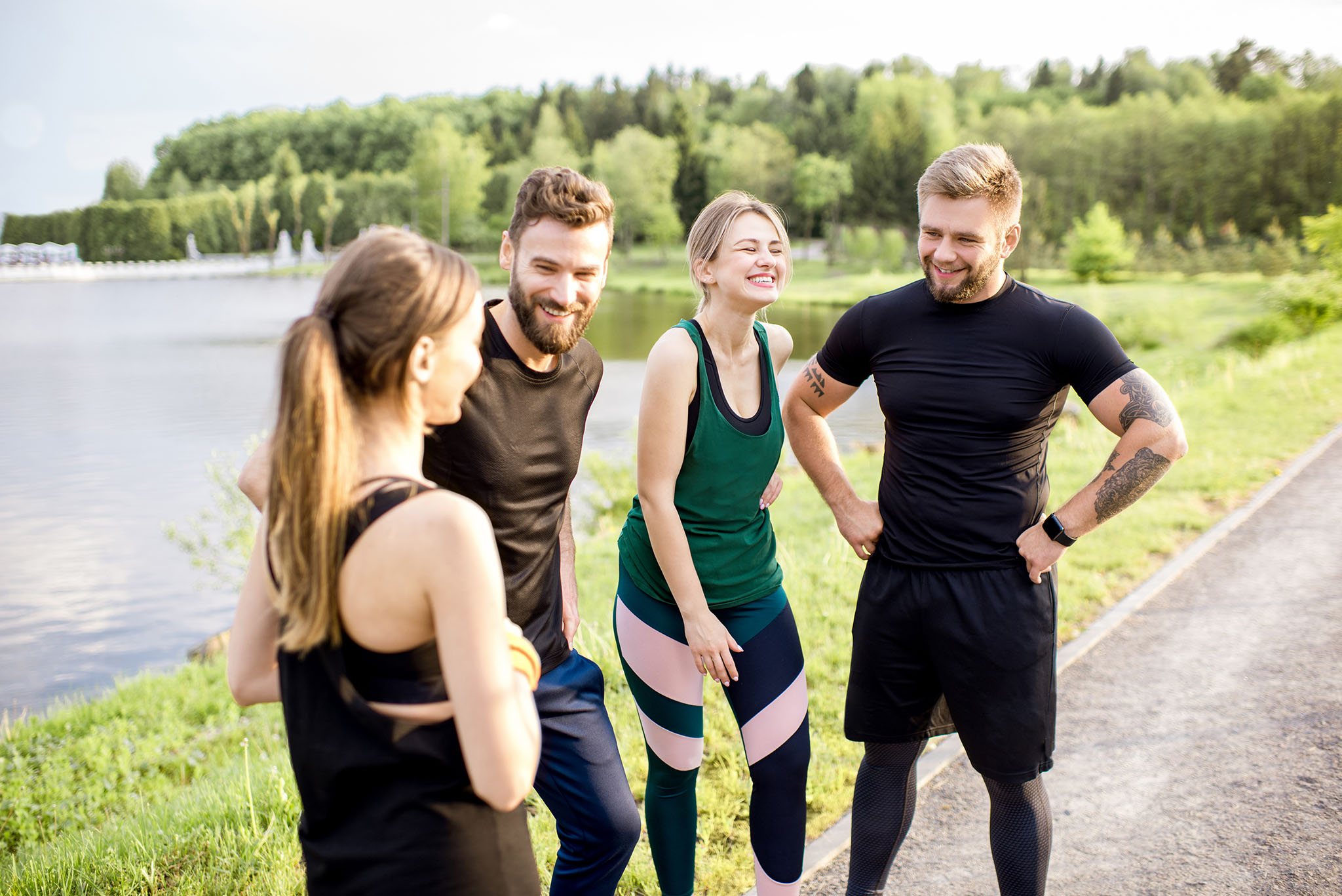 Sports team having fun standing together after the training outdors in the park near the lake