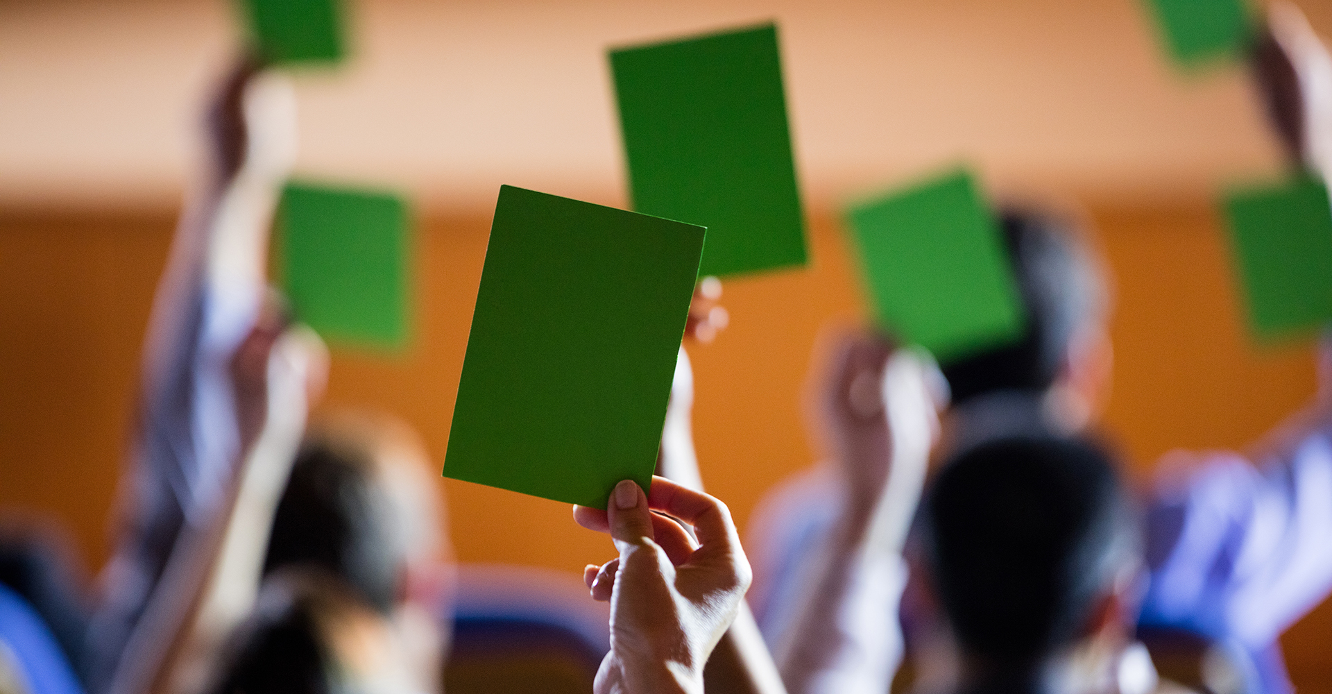 Rear view of business executives show their approval by raising hands at conference center